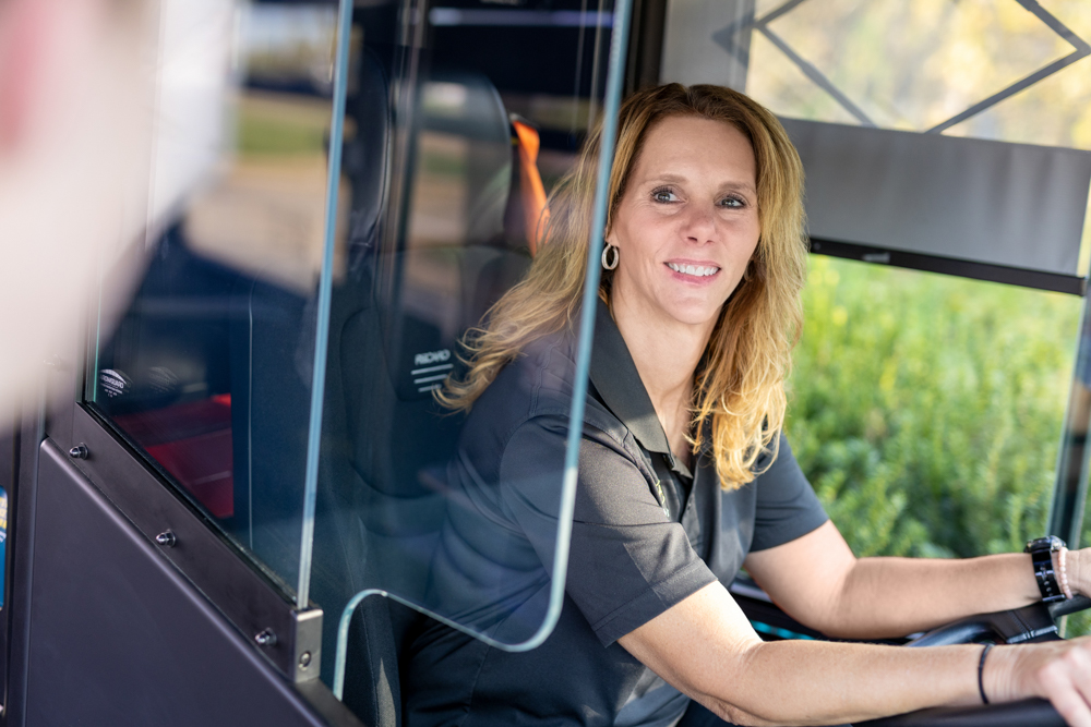 An operator sitting behind the wheel of a bus.
